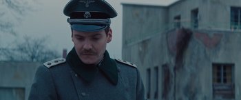 Movie still from “The Zookeeper's Wife” (2017), directed by Niki Caro – A man in a military uniform is looking down at the ground; Close Up shot, Over the shoulder angle