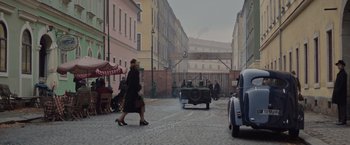 Movie still from “The Zookeeper's Wife” (2017), directed by Niki Caro – A woman is walking down the street with a handbag; Wide shot, Over the shoulder angle
