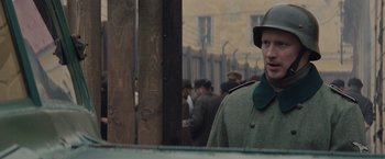 Movie still from “The Zookeeper's Wife” (2017), directed by Niki Caro – A man in a military uniform standing in front of a crowd; Medium shot, Over the shoulder angle