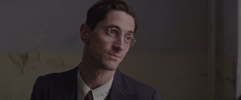 Movie still from “The Zookeeper's Wife” (2017), directed by Niki Caro – A person wearing a suit and glasses; Close Up shot, Over the shoulder angle