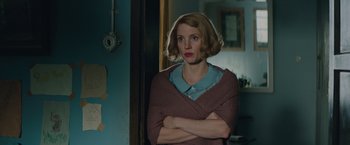 Movie still from “The Zookeeper's Wife” (2017), directed by Niki Caro – A woman standing with her arms crossed in front of a mirror; Medium shot, Over the shoulder angle