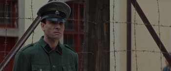 Movie still from “The Zookeeper's Wife” (2017), directed by Niki Caro – A man in a military uniform standing in front of a barbed wire fence; Close Up shot, Over the shoulder angle