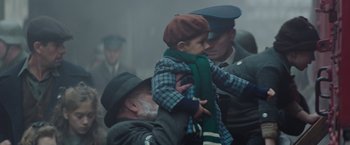 Movie still from “The Zookeeper's Wife” (2017), directed by Niki Caro – An old man holding a young boy wearing a green scarf; Medium shot, Over the shoulder angle