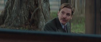 Movie still from “The Zookeeper's Wife” (2017), directed by Niki Caro – A man with a mustache sitting in front of a tree; Close Up shot, Over the shoulder angle