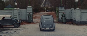 Movie still from “The Zookeeper's Wife” (2017), directed by Niki Caro – An old car is parked in front of a gate; Wide shot, High angle