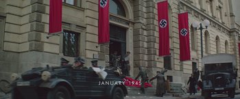 Movie still from “The Zookeeper's Wife” (2017), directed by Niki Caro – A group of men standing in front of a building; Extreme Wide shot, High angle