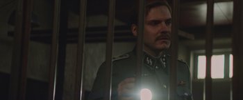 Movie still from “The Zookeeper's Wife” (2017), directed by Niki Caro – A man in a military uniform looking through bars of a jail cell; Close Up shot, Low angle