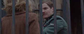 Movie still from “The Zookeeper's Wife” (2017), directed by Niki Caro – A man with a mustache is behind a fence; Close Up shot, Over the shoulder angle