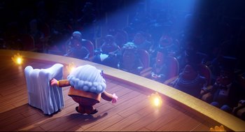 Movie still from “Captain Underpants: The First Epic Movie” (2017), directed by David Soren – A person is standing on a stage in front of an audience; Extreme Wide shot, Low angle