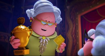 Movie still from “Captain Underpants: The First Epic Movie” (2017), directed by David Soren – An old woman holding a trophy and a gold coin in her hand; Medium shot, Over the shoulder angle