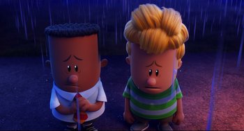Movie still from “Captain Underpants: The First Epic Movie” (2017), directed by David Soren – A couple of people that are sitting down in the rain; Medium shot, Low angle