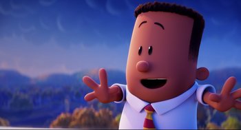 Movie still from “Captain Underpants: The First Epic Movie” (2017), directed by David Soren – A man in a suit and tie waving to the camera; Medium shot, Low angle