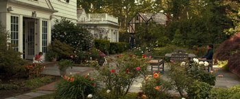 Movie still from “This Is Where I Leave You” (2014), directed by Shawn Levy – A person standing in a yard with a bench and flowers; Extreme Wide shot, High angle