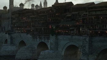 Movie still from “Game of Thrones” (2011), created by D.B. Weiss – An image of an old town with a bridge going over it; Extreme Wide shot, Low angle