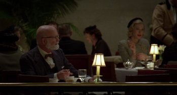 Movie still from “Carol” (2015), directed by Todd Haynes – An older man sitting at a table in front of a lamp; Medium shot, Over the shoulder angle