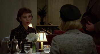 Movie still from “Carol” (2015), directed by Todd Haynes – Two people sitting at a table with a vase of flowers; Medium shot, Over the shoulder angle