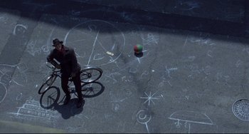 Movie still from “Carol” (2015), directed by Todd Haynes – A man riding a bike on top of a sidewalk; Extreme Wide shot, Overhead angle