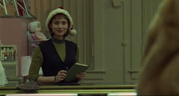 Movie still from “Carol” (2015), directed by Todd Haynes – A woman wearing a santa hat and holding a notebook; Medium shot, Over the shoulder angle