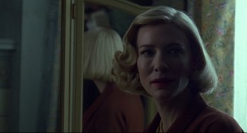 Movie still from “Carol” (2015), directed by Todd Haynes – A woman with blonde curly hair standing in front of a mirror; Close Up shot, Over the shoulder angle