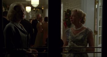 Movie still from “Carol” (2015), directed by Todd Haynes – A group of people standing in a room with lights on; Medium shot, Over the shoulder angle