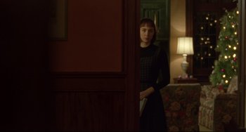 Movie still from “Carol” (2015), directed by Todd Haynes – A woman standing in front of a door holding a book in her hand; Medium shot, Over the shoulder angle