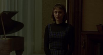Movie still from “Carol” (2015), directed by Todd Haynes – A woman in a plaid dress standing next to a door; Medium shot, Over the shoulder angle