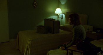 Movie still from “Carol” (2015), directed by Todd Haynes – A woman sitting on a bed next to a suitcase; Wide shot, High angle