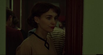 Movie still from “Carol” (2015), directed by Todd Haynes – A woman standing next to a door in a room; Close Up shot, Over the shoulder angle