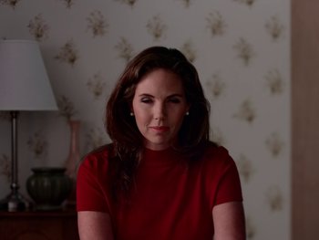Movie still from “Casting JonBenet” (2017), directed by Kitty Green – A woman wearing a red shirt in front of a wall; Medium shot, Low angle