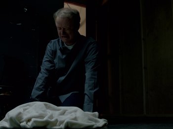 Movie still from “Casting JonBenet” (2017), directed by Kitty Green – An older man kneeling down next to a blanket; Medium shot, High angle