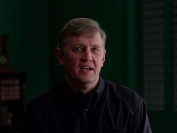 Movie still from “Casting JonBenet” (2017), directed by Kitty Green – An older man in a black shirt is looking at the camera; Close Up shot, Low angle