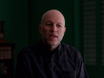Movie still from “Casting JonBenet” (2017), directed by Kitty Green – A man with a bald head wearing a button up shirt; Close Up shot, Low angle