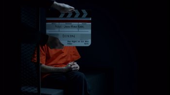 Movie still from “Casting JonBenet” (2017), directed by Kitty Green – A man in an orange shirt holding a clapperboard in front of him; Medium shot, Over the shoulder angle