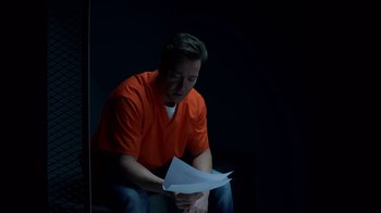 Movie still from “Casting JonBenet” (2017), directed by Kitty Green – A man in an orange shirt is holding papers; Medium shot, High angle