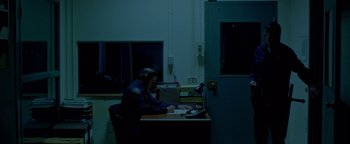 Movie still from “Casting JonBenet” (2017), directed by Kitty Green – A man sitting at a desk in front of a computer; Wide shot, Low angle