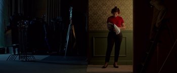 Movie still from “Casting JonBenet” (2017), directed by Kitty Green – A woman standing in front of a wall holding papers; Wide shot, Low angle