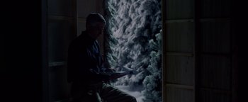 Movie still from “Casting JonBenet” (2017), directed by Kitty Green – A man sitting in front of a window looking at a book; Medium shot, Over the shoulder angle