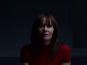 Movie still from “Casting JonBenet” (2017), directed by Kitty Green – A woman in a red shirt is in a dark room; Close Up shot, Low angle