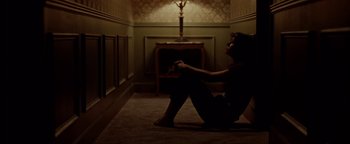 Movie still from “Casting JonBenet” (2017), directed by Kitty Green – A woman sitting on the ground in a dark room; Wide shot, High angle