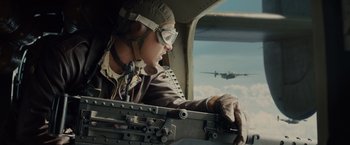Movie still from “Unbroken” (2014), directed by Angelina Jolie – A man in a fighter jet cockpit looking at a plane; Medium shot, Low angle