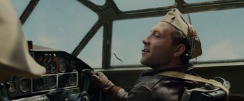 Movie still from “Unbroken” (2014), directed by Angelina Jolie – A man driving a car wearing a hat; Close Up shot, Low angle