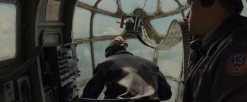 Movie still from “Unbroken” (2014), directed by Angelina Jolie – A man in a leather jacket looking out the window of an airplane; Medium shot, Low angle