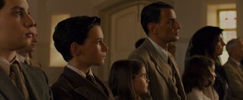 Movie still from “Unbroken” (2014), directed by Angelina Jolie – A man and two young girls in a room; Medium shot, Low angle