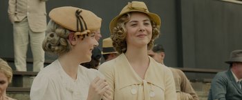 Movie still from “Unbroken” (2014), directed by Angelina Jolie – Two young women wearing hats smiling for the camera; Close Up shot, Low angle