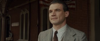 Movie still from “Unbroken” (2014), directed by Angelina Jolie – A man wearing a suit and tie looking up; Close Up shot, Low angle