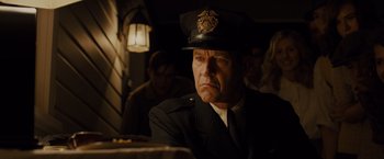 Movie still from “Unbroken” (2014), directed by Angelina Jolie – A man in a police uniform sitting at a table; Close Up shot, Low angle