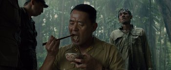 Movie still from “Unbroken” (2014), directed by Angelina Jolie – A man eating something while holding a wooden spoon; Medium shot, Low angle