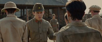 Movie still from “Unbroken” (2014), directed by Angelina Jolie – A group of men in military uniforms standing next to each other; Medium shot, Over the shoulder angle
