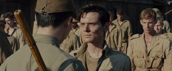Movie still from “Unbroken” (2014), directed by Angelina Jolie – A man in a military uniform looking at another man in a uniform; Close Up shot, Over the shoulder angle