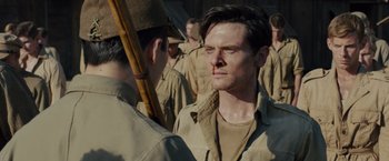 Movie still from “Unbroken” (2014), directed by Angelina Jolie – A man in a military uniform is looking at another man in a uniform; Close Up shot, Over the shoulder angle